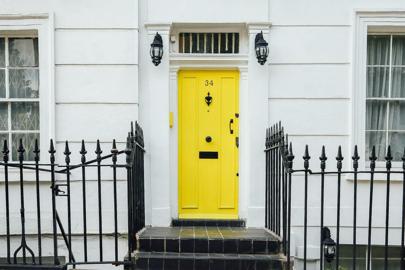 A single bright yellow door set into a row of plain white facades — the one thing on the street you actually remember.
